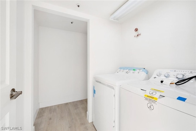 laundry area with washer and clothes dryer and light hardwood / wood-style flooring