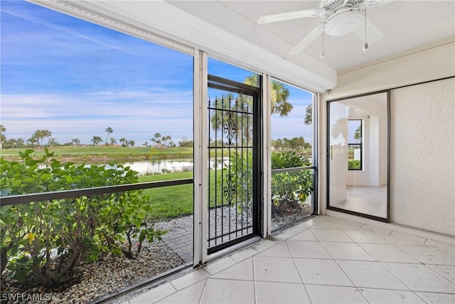 unfurnished sunroom featuring ceiling fan and a water view