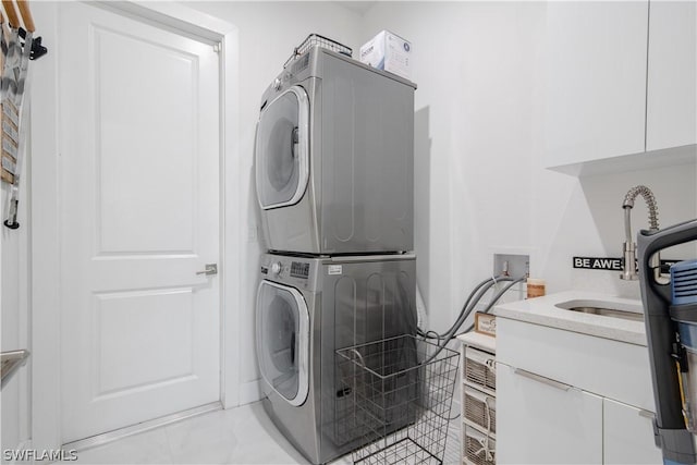 clothes washing area with sink, cabinets, and stacked washer / drying machine