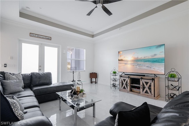 living room with a raised ceiling, ceiling fan, french doors, and ornamental molding