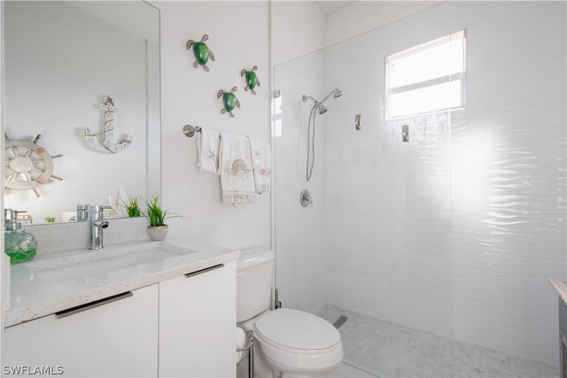 bathroom with tiled shower, vanity, and toilet