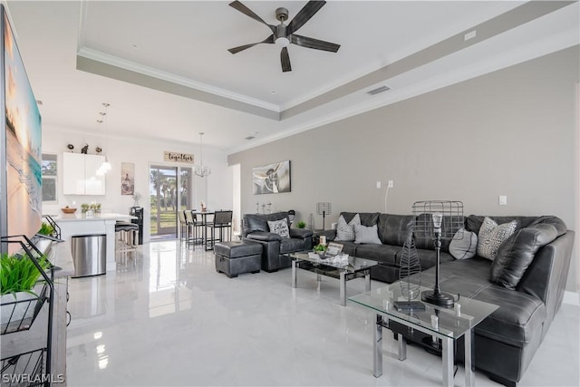 living room featuring ceiling fan with notable chandelier, a raised ceiling, and ornamental molding