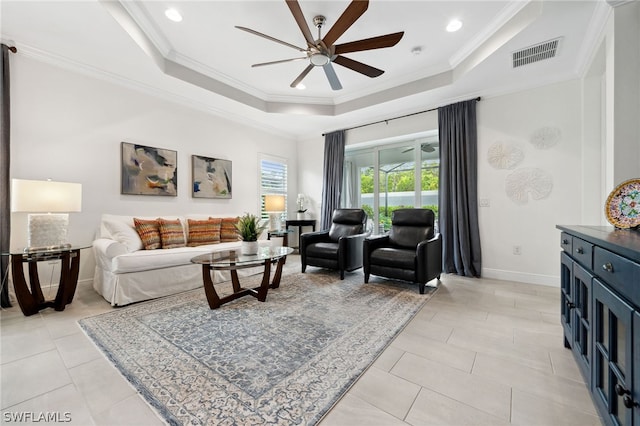 living room featuring a tray ceiling, ceiling fan, and ornamental molding