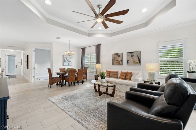 living room featuring ceiling fan, a healthy amount of sunlight, crown molding, and a tray ceiling