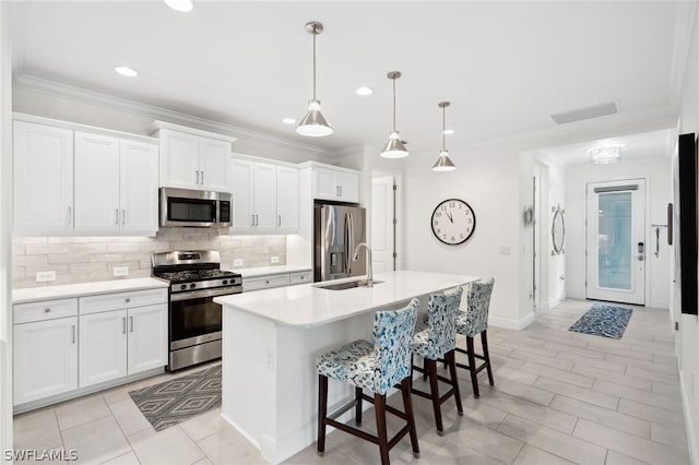 kitchen with white cabinets, decorative light fixtures, stainless steel appliances, and a center island with sink