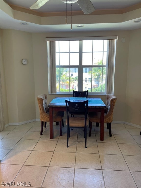 tiled dining room featuring ornamental molding and a tray ceiling