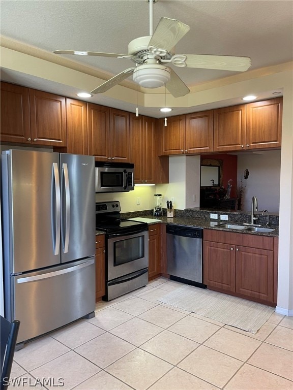 kitchen with ceiling fan, sink, dark stone counters, light tile patterned flooring, and appliances with stainless steel finishes