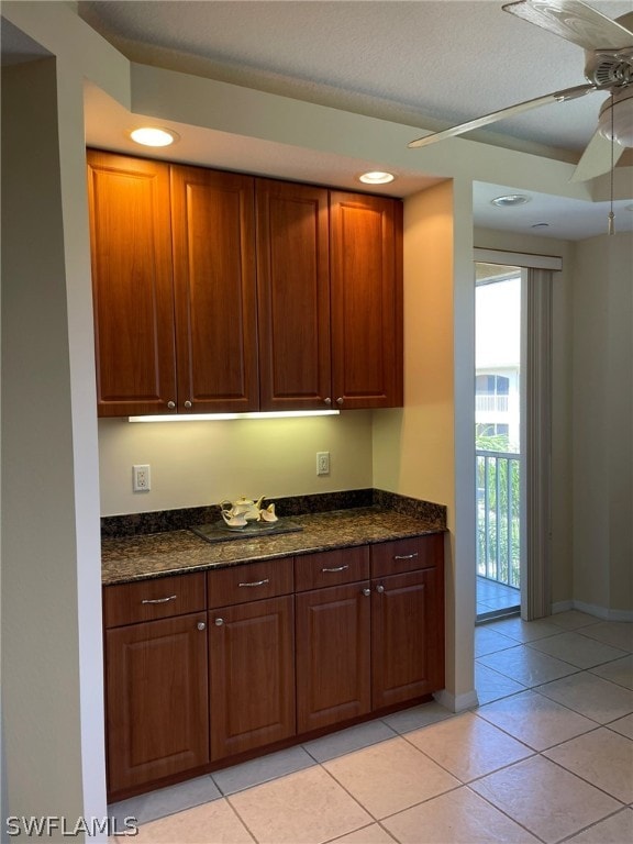 kitchen featuring light tile patterned floors, ceiling fan, and dark stone counters