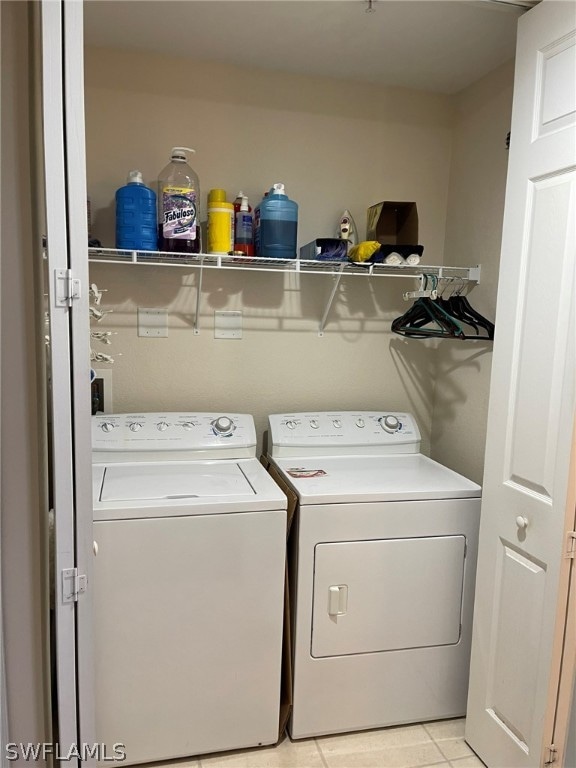 washroom with washing machine and clothes dryer and light tile patterned flooring