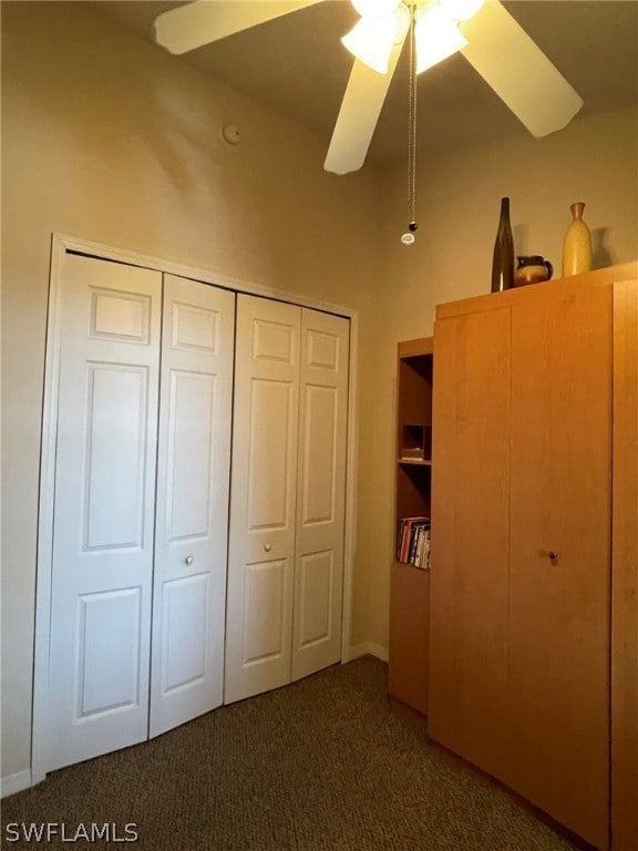 unfurnished bedroom featuring ceiling fan, dark carpet, and a closet