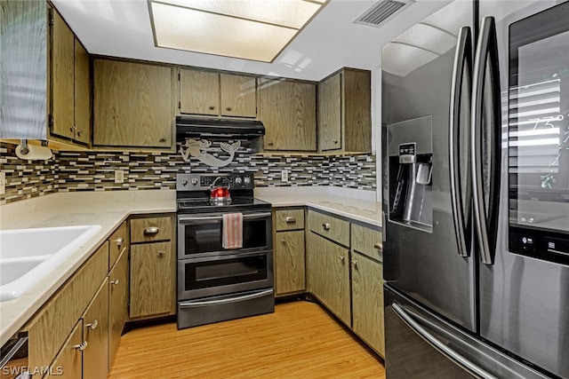 kitchen featuring stainless steel appliances, light wood-type flooring, sink, and tasteful backsplash