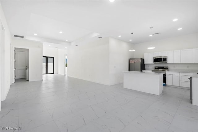 kitchen featuring a kitchen island, a raised ceiling, white cabinetry, and appliances with stainless steel finishes