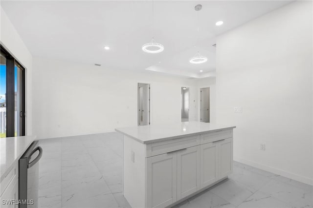 kitchen featuring a raised ceiling, white cabinetry, and hanging light fixtures