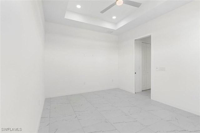 unfurnished room featuring ceiling fan and a raised ceiling