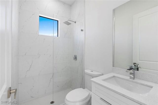 bathroom featuring vanity, toilet, and a tile shower