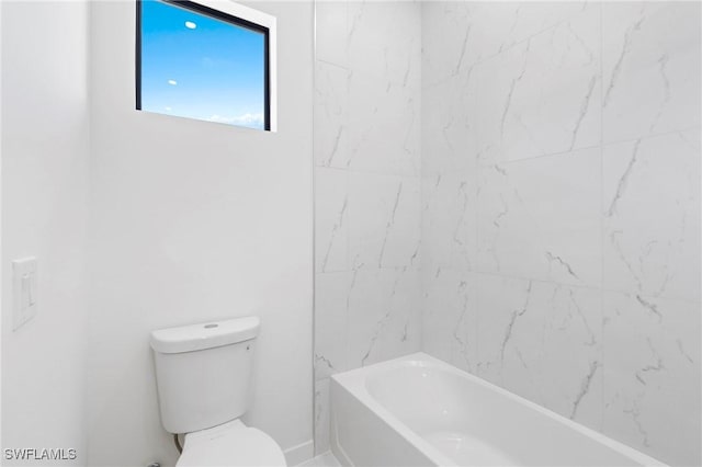 bathroom featuring tiled shower / bath combo and toilet