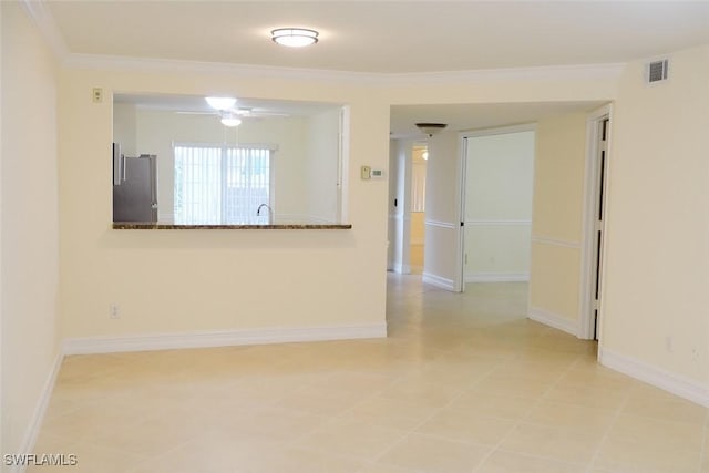 spare room with ceiling fan, ornamental molding, visible vents, and baseboards