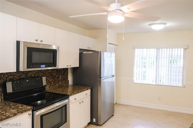 kitchen with baseboards, white cabinets, dark stone counters, decorative backsplash, and stainless steel appliances