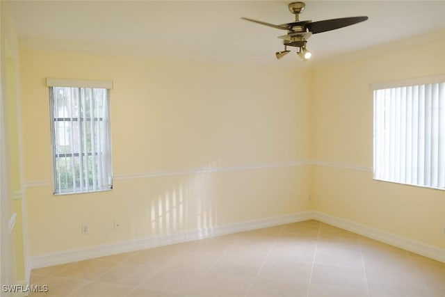 spare room with light tile patterned floors, ceiling fan, and baseboards