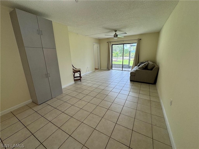 unfurnished living room featuring ceiling fan, light tile patterned flooring, and a textured ceiling