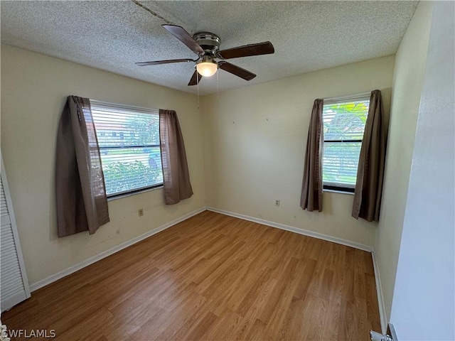 unfurnished room with a wealth of natural light, ceiling fan, a textured ceiling, and light wood-type flooring