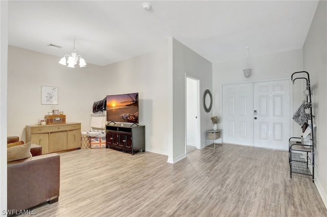 living room featuring a chandelier, light wood finished floors, visible vents, and baseboards