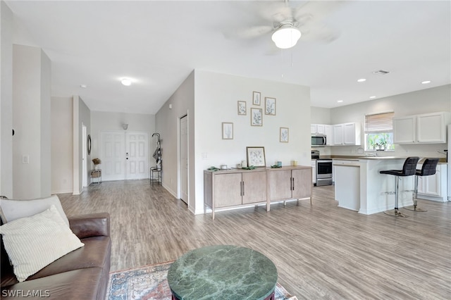 living room with ceiling fan and light hardwood / wood-style flooring