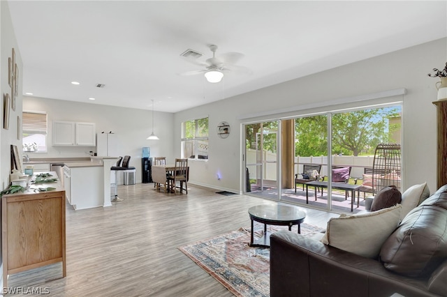 living area with ceiling fan, recessed lighting, visible vents, baseboards, and light wood-type flooring