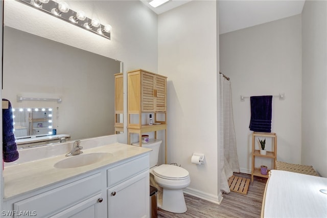 bathroom featuring a shower with shower curtain, toilet, vanity, wood finished floors, and baseboards