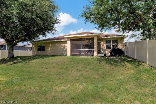 rear view of property with a yard, a fenced backyard, a sunroom, and stucco siding