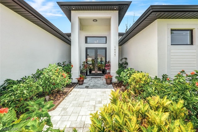 view of exterior entry featuring french doors and stucco siding