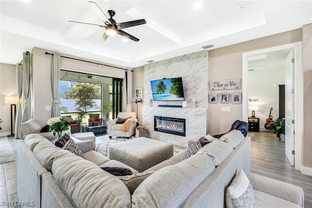 living area featuring a premium fireplace, a ceiling fan, baseboards, visible vents, and light wood-style floors