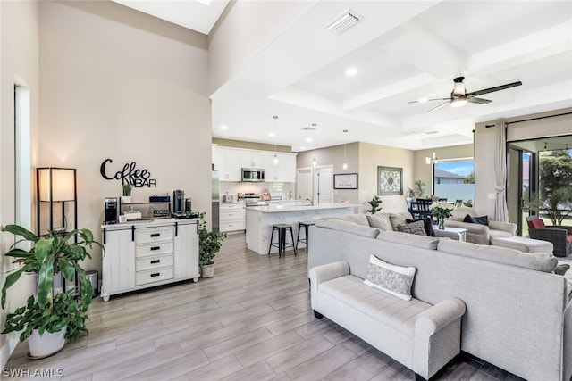 living room with ceiling fan, recessed lighting, visible vents, light wood-style floors, and beamed ceiling