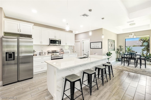 kitchen with a sink, visible vents, white cabinets, appliances with stainless steel finishes, and tasteful backsplash