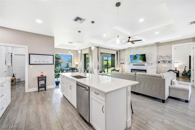 kitchen featuring visible vents, dishwasher, white cabinetry, a sink, and a high end fireplace