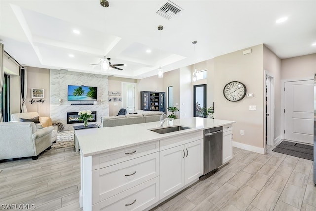 kitchen featuring a fireplace, a sink, visible vents, open floor plan, and stainless steel dishwasher