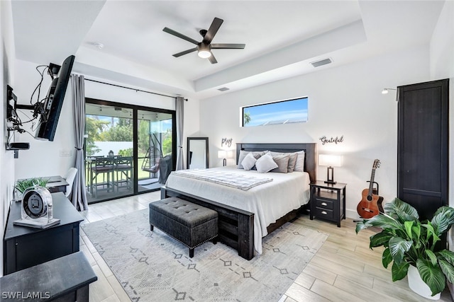 bedroom with access to outside, multiple windows, and a raised ceiling