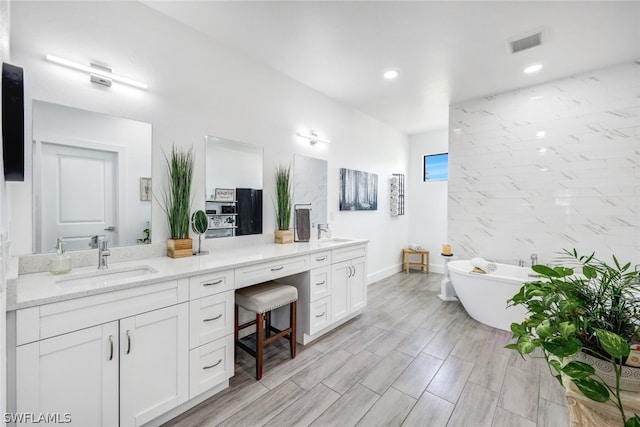 bathroom featuring recessed lighting, visible vents, a freestanding bath, vanity, and wood finished floors