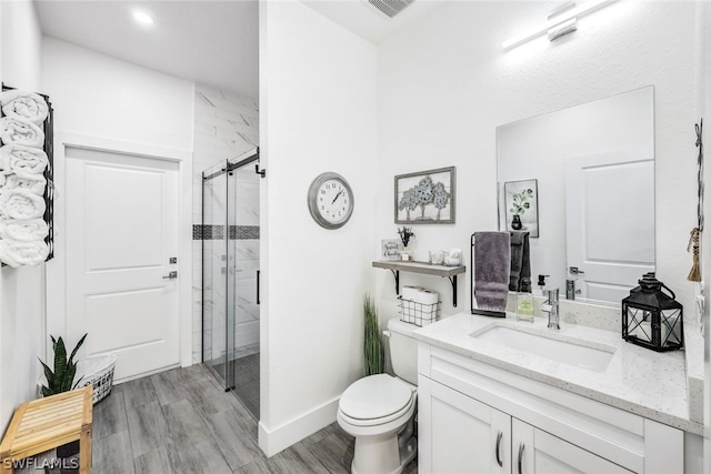 bathroom featuring toilet, wood finished floors, vanity, baseboards, and a shower stall