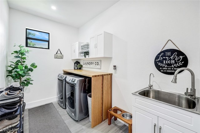 laundry room with washer and dryer, cabinet space, a sink, and baseboards