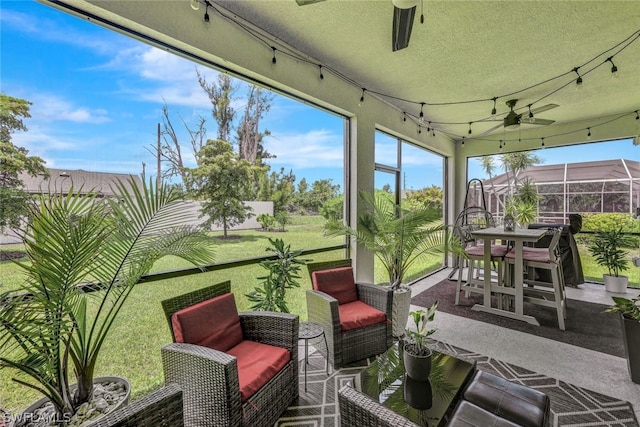 sunroom featuring a healthy amount of sunlight, rail lighting, and a ceiling fan