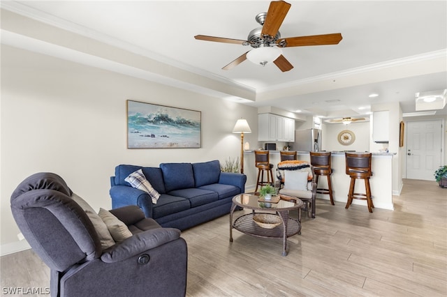 living room featuring ceiling fan, light hardwood / wood-style floors, a tray ceiling, and crown molding