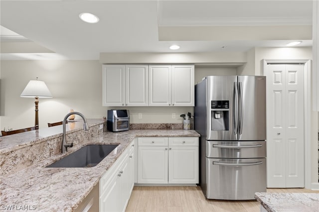 kitchen with white cabinets, crown molding, sink, and stainless steel fridge with ice dispenser