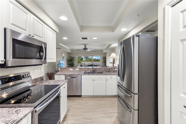 kitchen with white cabinets, a raised ceiling, crown molding, sink, and appliances with stainless steel finishes