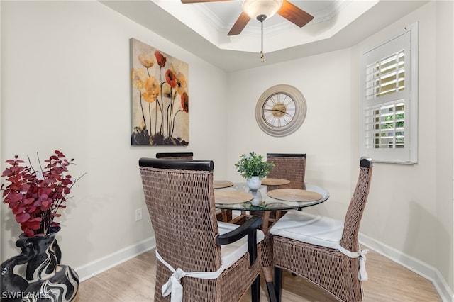 dining space featuring a tray ceiling, crown molding, light hardwood / wood-style flooring, and ceiling fan