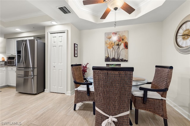 dining space with a raised ceiling, ceiling fan, light hardwood / wood-style flooring, and crown molding