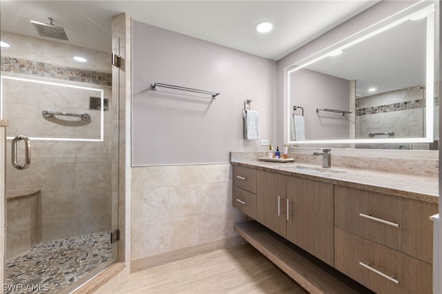 bathroom with hardwood / wood-style floors, vanity, and an enclosed shower