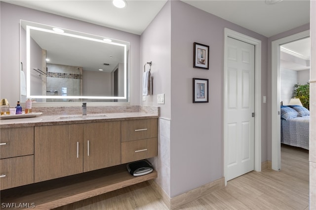 bathroom featuring hardwood / wood-style floors, vanity, and tiled shower