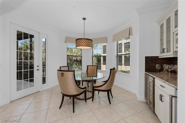 tiled dining space with beverage cooler and crown molding