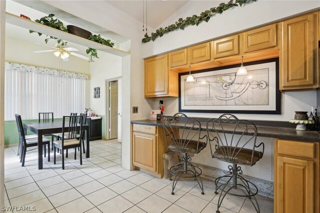 kitchen with ceiling fan, light tile patterned flooring, pendant lighting, and lofted ceiling